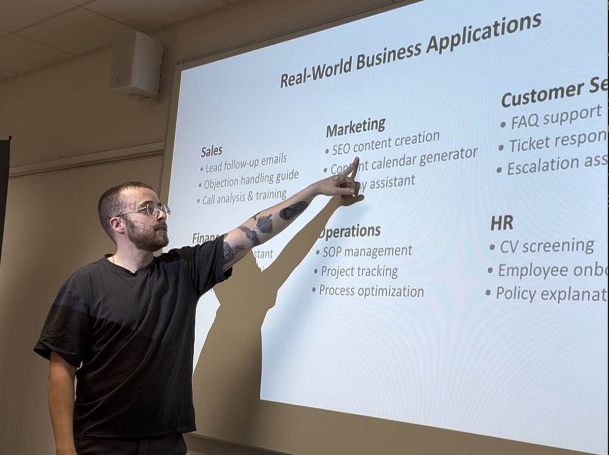 George delivering an AI workshop, pointing at Real-World Business Applications